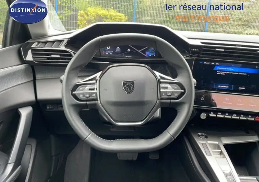 Vue intérieure centrée sur le volant cuir multifonction d’une Peugeot 408 gris selenium, avec tableau de bord digital et écran tactile.