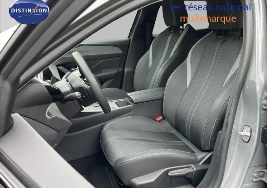 Vue intérieure côté conducteur de la Peugeot 408 gris selenium, sièges tissu et cuir avec surpiqûres contrastées.