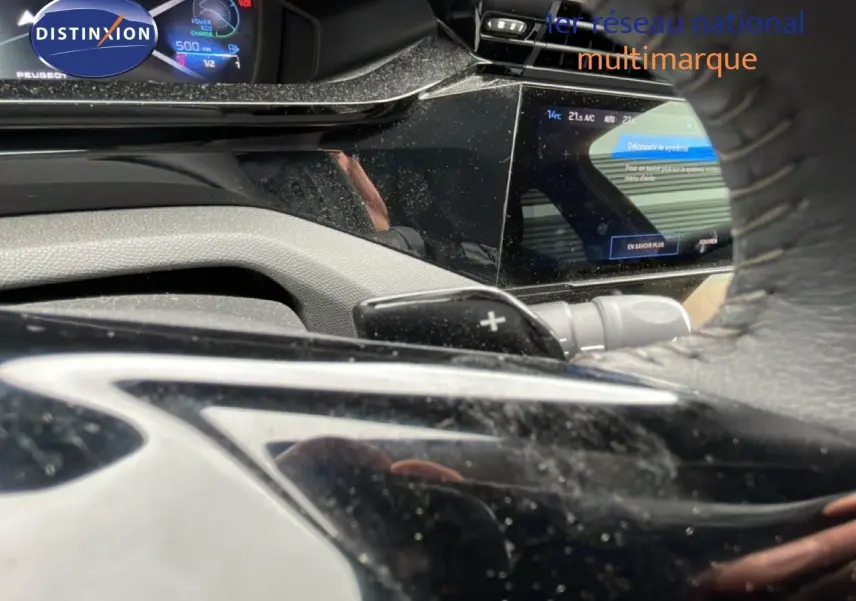 Vue rapprochée du tableau de bord et du volant noir de la Peugeot 408 1.2 Hybrid 2025 avec écran digital et palettes au volant.