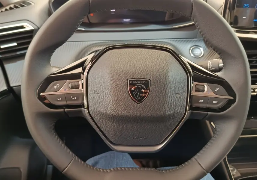 Volant cuir noir de Peugeot 208 électrique 2024 vu de face, avec commandes intégrées et bouton démarrage visible.