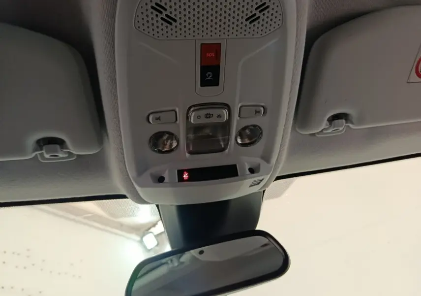 Plafonnier intérieur avec commandes d’éclairage et bouton SOS, vue centrée vers le rétroviseur intérieur d’une Peugeot 208 blanche.