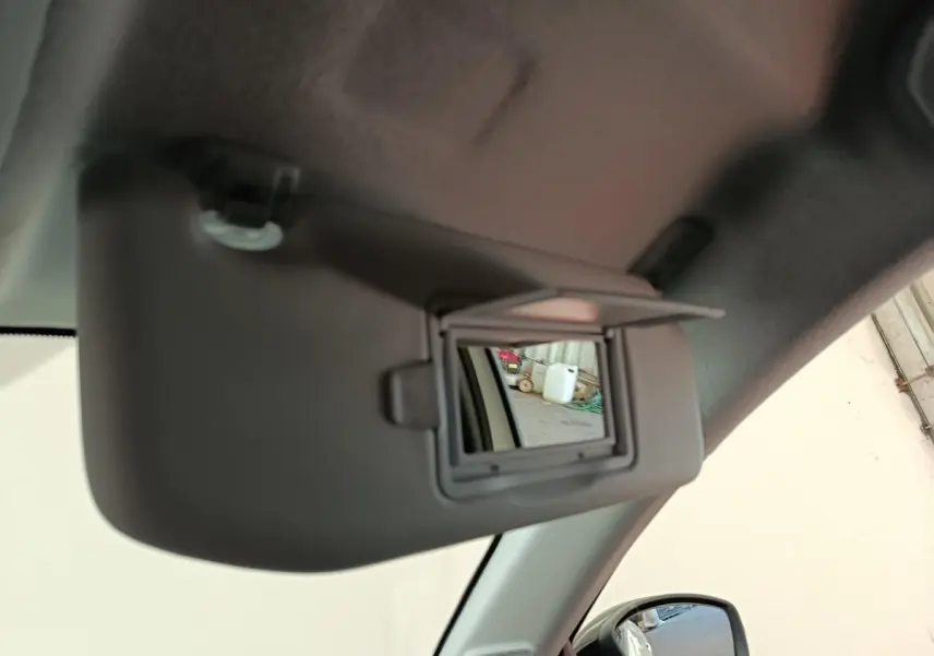 Détail intérieur du pare-soleil avec miroir ouvert côté conducteur d'une Peugeot 208 électrique blanche 2024.