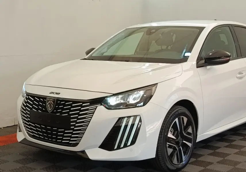 Peugeot 208 électrique blanche vue 3/4 avant droit, avec phares LED allumés et calandre distinctive noire.