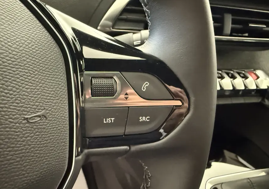 Gros plan sur les commandes gauche du volant cuir noir du Peugeot 3008 2023, avec boutons LIST, SRC et décrocher.
