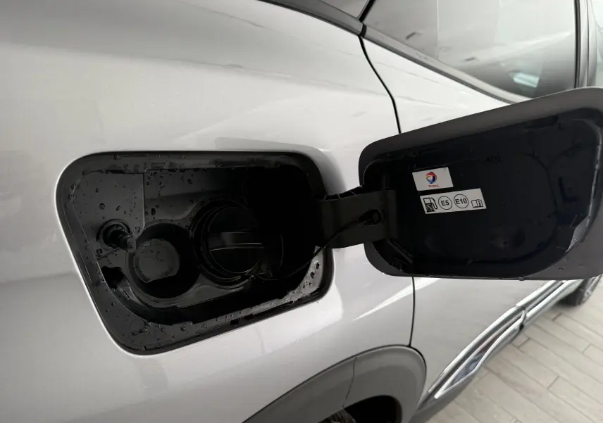 Bouchon de réservoir essence ouvert côté gauche d’un Peugeot 3008 gris Artense Metal, avec étiquette carburants E5 et E10 visible.