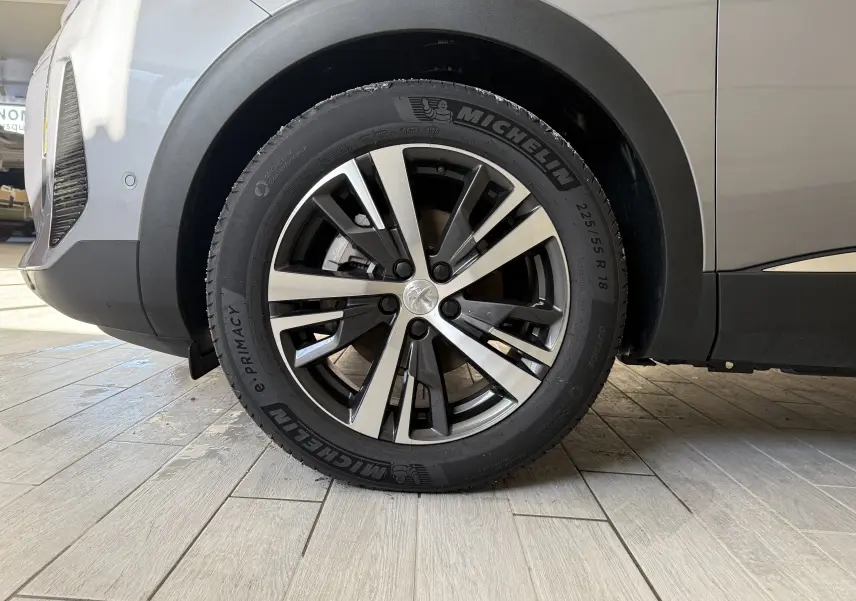 Gros plan sur la roue avant droite d'un Peugeot 3008 gris Artense métal avec jante alliage et pneu Michelin.