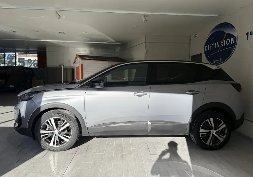 Profil côté gauche d'un Peugeot 3008 gris Artense métal 2023 en showroom avec jantes alliage et vitres teintées.