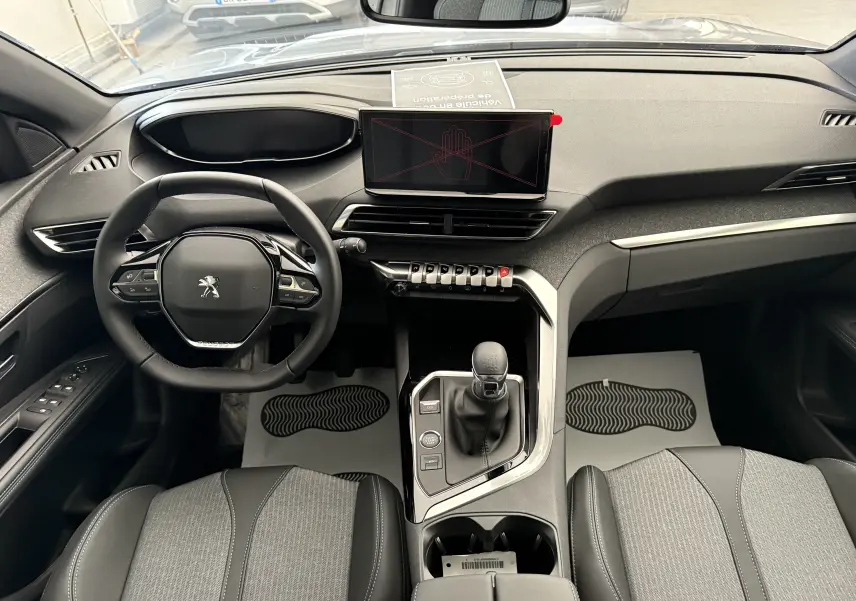 Vue intérieure frontale du Peugeot 3008 2023 avec tableau de bord moderne, volant compact et écran tactile central.