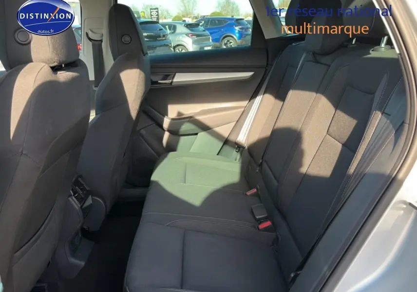 Vue intérieure côté droit des sièges arrière noirs du Skoda Karoq gris 2025 avec accoudoir central et ceintures visibles.