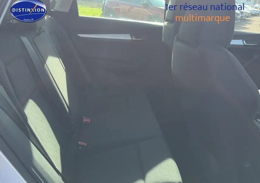 Vue intérieure côté arrière gauche du Skoda Karoq gris, montrant la banquette arrière et les sièges avant.