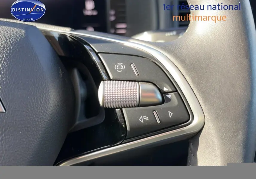 Gros plan sur les commandes multifonctions en métal et plastique noir du volant cuir d'une Skoda Karoq gris 2025.