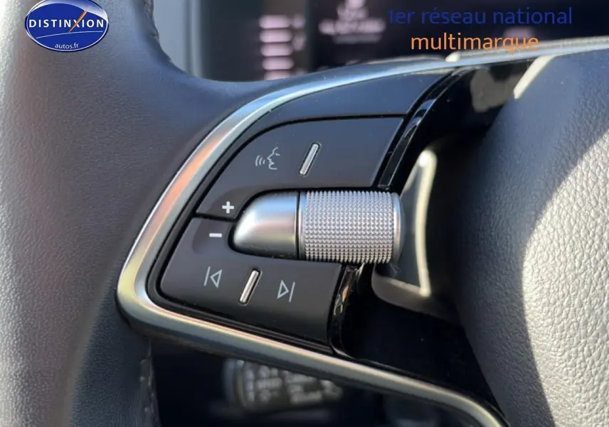 Gros plan sur les commandes audio et vocales au volant cuir noir du Skoda Karoq gris 2025.