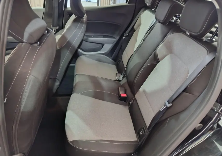 Vue intérieure côté droit des sièges arrière gris et noirs d'une Renault Clio noire, montrant les ceintures et appuie-têtes.