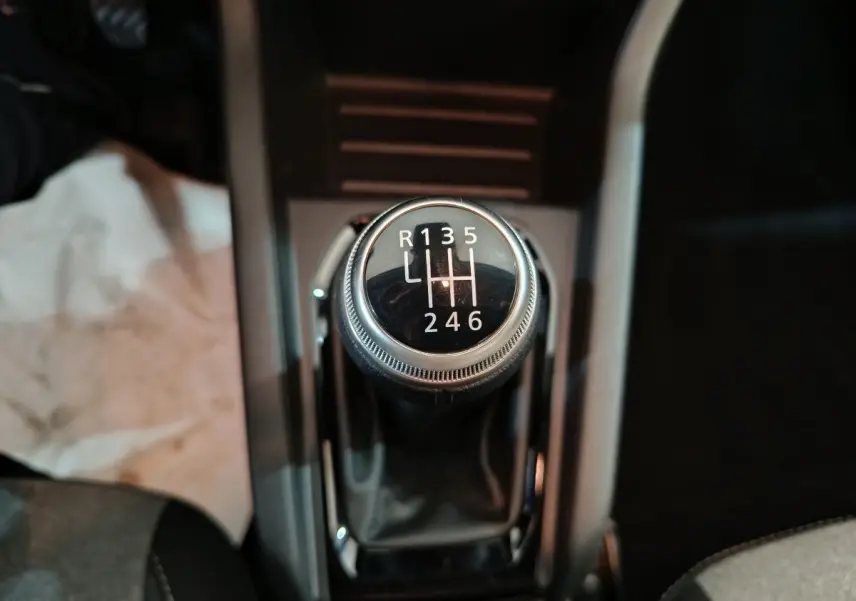 Gros plan sur le levier de vitesses manuel noir de la Renault Clio Evolution Blue dCi 100, intérieur sombre.