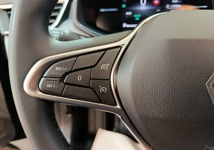 Gros plan sur les commandes du régulateur de vitesse au volant cuir noir d'une Renault Clio Evolution Blue dCi 100 de 2025.
