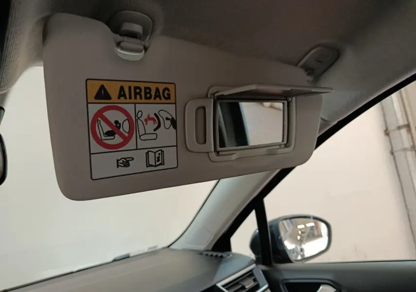 Vue intérieure côté conducteur sur le pare-soleil beige avec miroir et avertissement airbag de la Renault Clio noire.