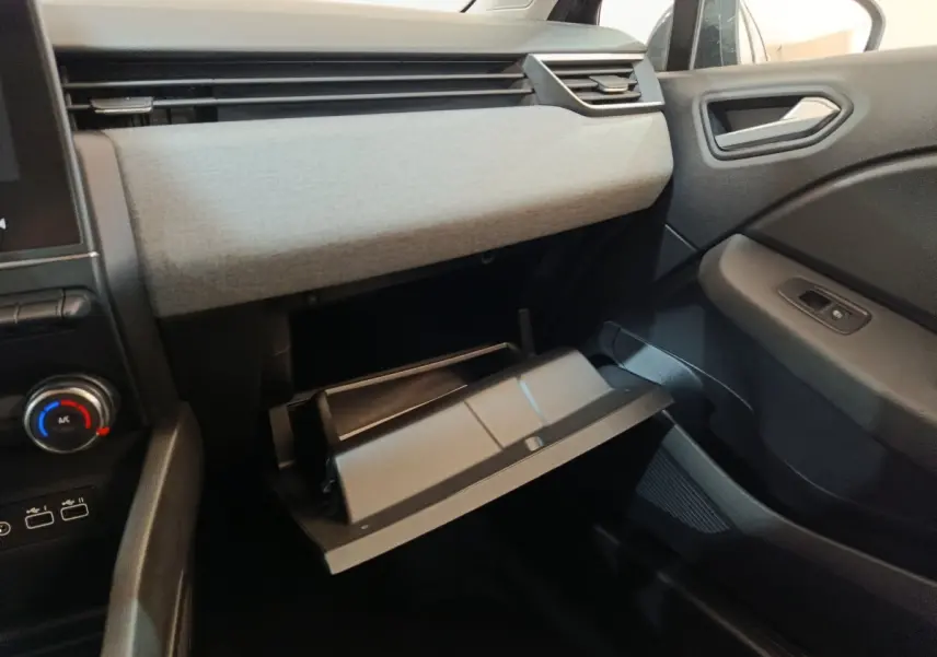 Intérieur de la Renault Clio Evolution Blue dCi 100 2025, vue côté passager sur la boîte à gants ouverte et tableau de bord gris clair.