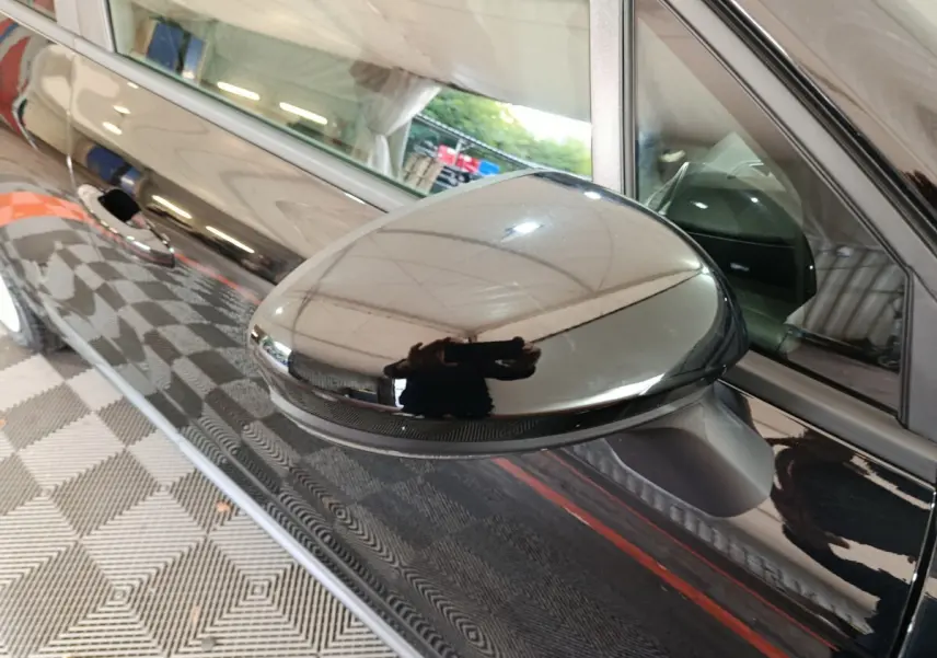 Rétroviseur extérieur droit noir brillant de Renault Clio Evolution Blue dCi 100, vue rapprochée sur la portière noire.