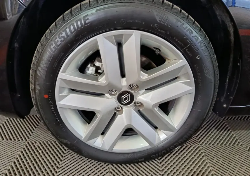Gros plan sur la roue avant droite d'une Renault Clio noire 2025, avec jante alliage argent et pneu Bridgestone Turanza.