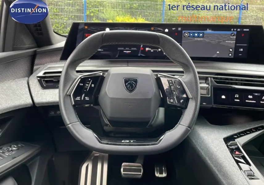 Vue intérieure frontale du volant GT en cuir perforé et des écrans numériques larges du Peugeot 3008 gris Artense 2025.