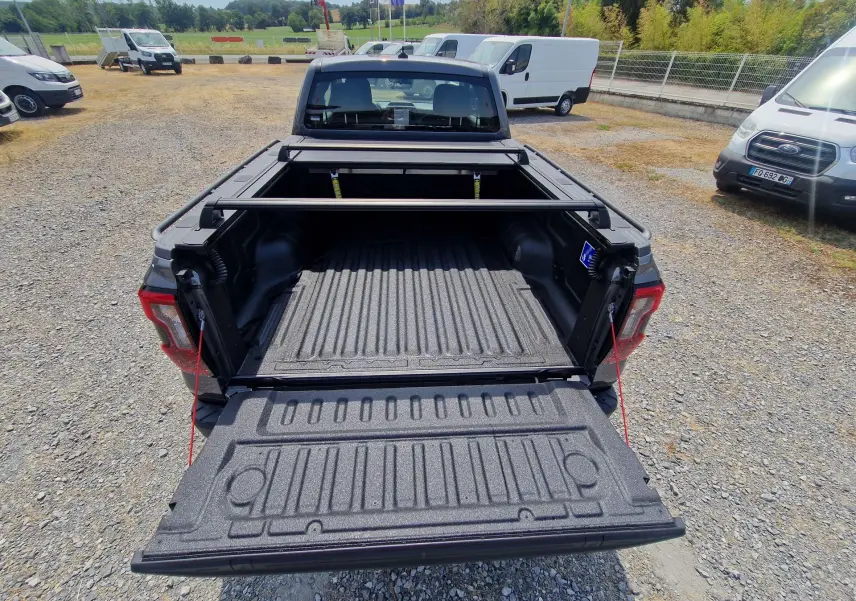 Vue arrière du Ford Ranger Super Cabine gris carbone avec plateau ouvert, rideau rigide coulissant et barres de protection visibles.