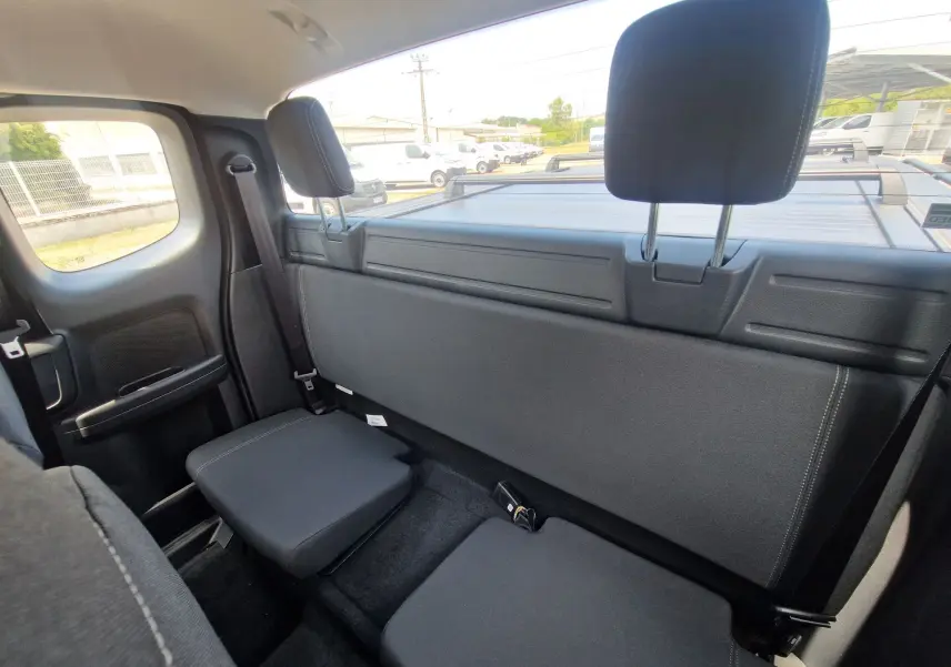 Vue intérieure arrière du Ford Ranger Super Cabine gris carbone, montrant les sièges rabattus et la fenêtre arrière.