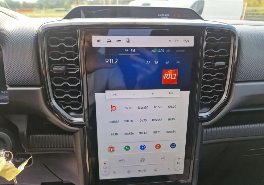 Vue intérieure centrée sur l'écran tactile 12,4'' du Ford Ranger Super Cabine gris carbone, avec commandes climatisation visibles.