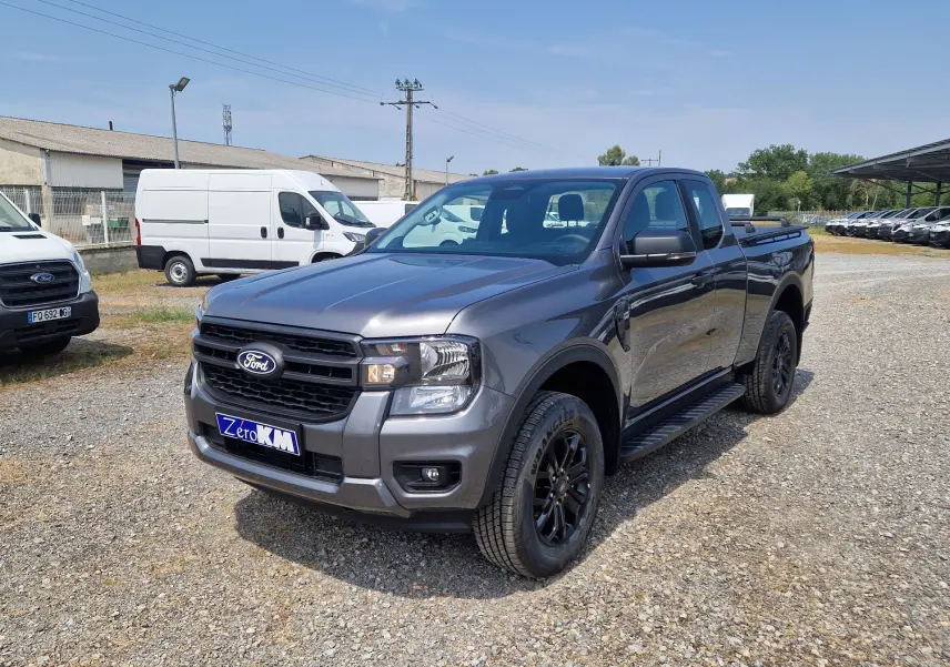 Ford Ranger Super Cabine gris carbone vu en 3/4 avant droit, avec marchepieds et jantes noires.