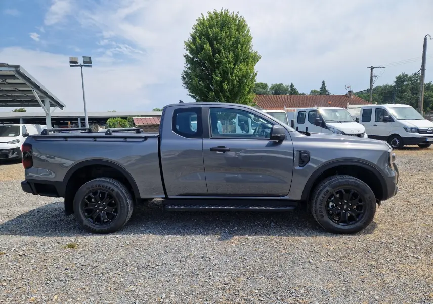 Ford Ranger Super Cabine gris carbone vu de profil côté gauche, avec marchepied et plateau couvert par un rideau rigide.