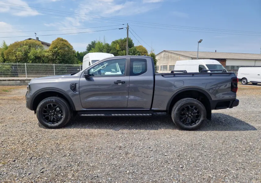 Ford Ranger Super Cabine gris carbone vu de profil côté gauche, avec marchepied et barres sur le plateau.