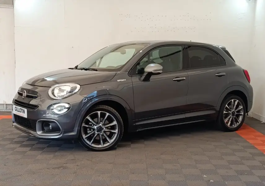 Fiat 500X gris foncé vue de profil droit en intérieur, avec jantes alliage et rétroviseurs argentés.