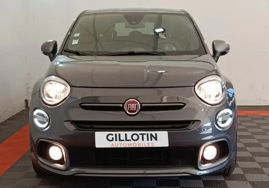 Vue frontale d'une Fiat 500X gris foncé avec feux LED allumés et logo Fiat bien visible sur calandre.