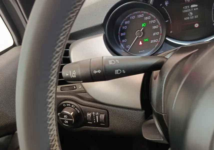 Vue rapprochée du tableau de bord côté gauche du Fiat 500X gris foncé, avec commandes d'éclairage et compteur visible.