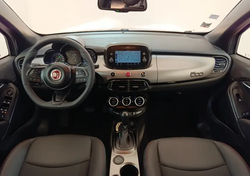 Vue intérieure avant de la Fiat 500X 2021, tableau de bord gris clair avec écran tactile et volant multifonctions noir.