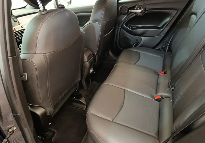 Vue intérieure arrière côté gauche de la Fiat 500X 2021, sièges en cuir noir avec surpiqûres rouges.