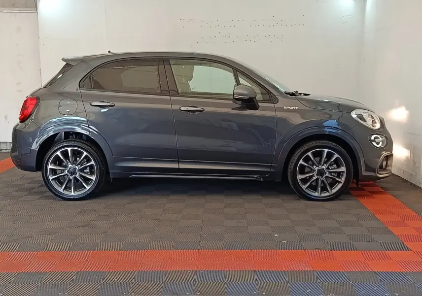 Profil droit d'une FIAT 500X Sport gris foncé avec jantes alliage et rétroviseurs ton caisse, en intérieur.