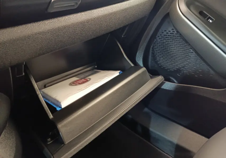 Vue intérieure côté passager du coffre à gants ouvert avec manuel FIAT visible dans un Fiat 500X gris foncé.