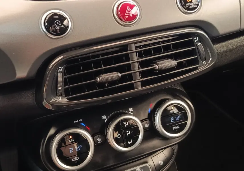Détail du tableau de bord gris foncé de la Fiat 500X 2021 montrant les commandes de climatisation automatique bi-zone.