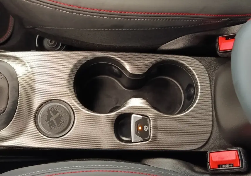 Gros plan sur la console centrale grise avec porte-gobelets et frein à main électrique de la Fiat 500X gris foncé.