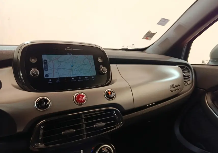 Vue intérieure du tableau de bord gris clair de la Fiat 500X 2021 avec écran tactile de navigation et commandes centrales.