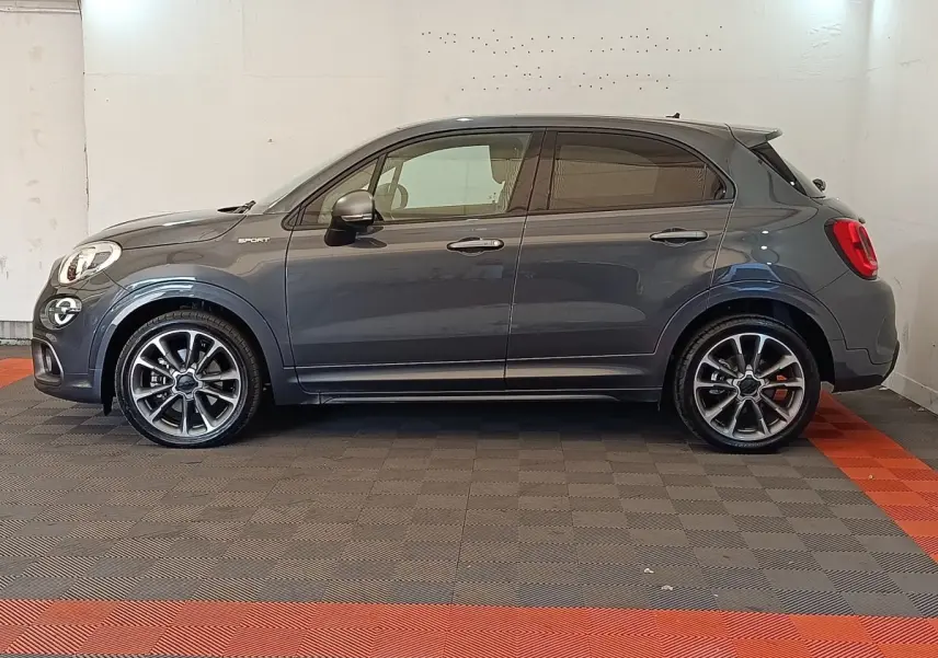 Profil droit d'un FIAT 500X gris foncé 2021 version Sport avec jantes alliage et logo "Sport" sur aile avant.