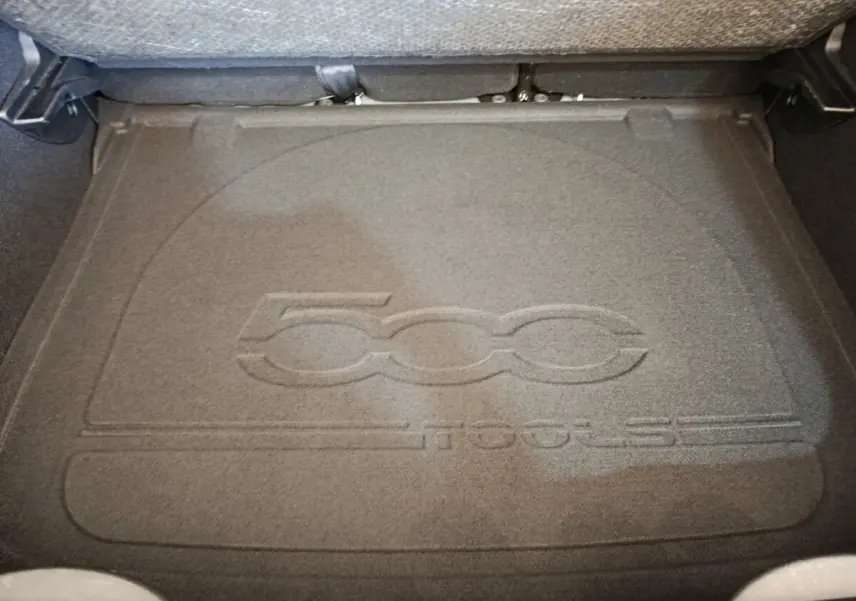 Vue plongeante sur le coffre avec tapis gris foncé embossé du logo 500X, banquette arrière rabattue visible en arrière-plan.