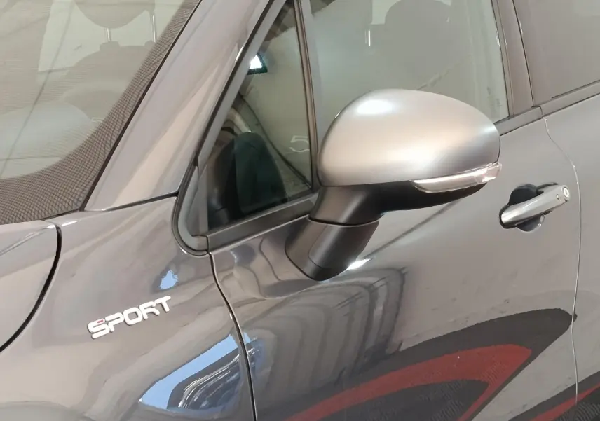 Gros plan sur le rétroviseur droit gris argenté et l’inscription Sport sur la porte gris foncé d’un Fiat 500X.