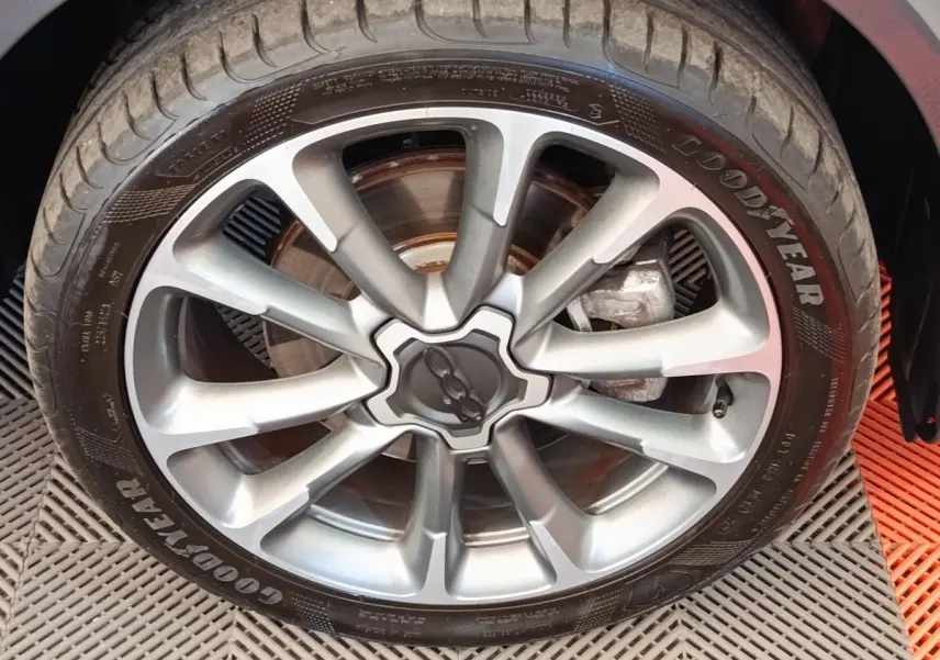 Gros plan sur la jante alliage gris argenté et pneu Goodyear d'une Fiat 500X gris foncé, vue côté roue arrière.