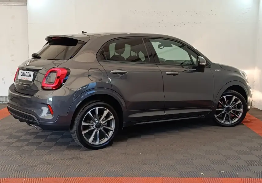 Vue latérale droite d'un FIAT 500X gris foncé avec jantes alliage et badge Sport sur l'aile avant.