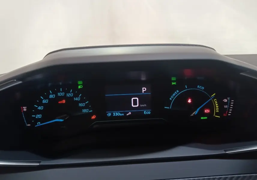 Tableau de bord numérique de Peugeot 208 électrique 2024 affichant vitesse, autonomie et indicateurs énergie en vue frontale.