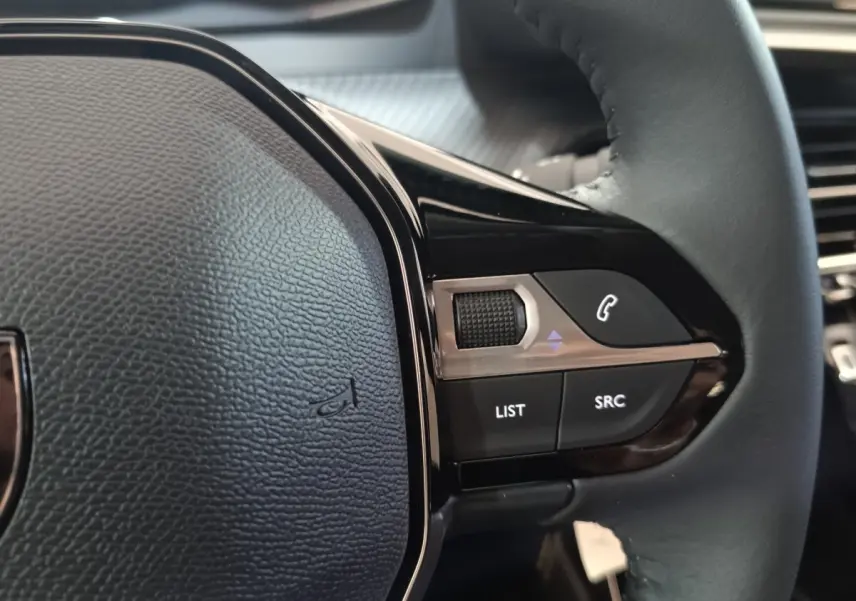 Gros plan sur le volant cuir multifonctions côté droit du Peugeot 208 électrique 2024, avec commandes intégrées.