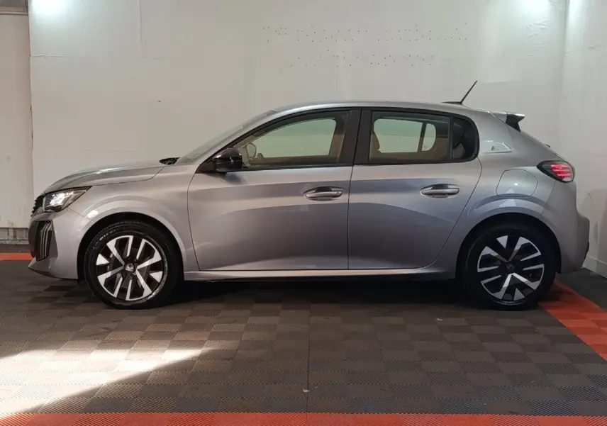 Profil côté gauche d'une Peugeot 208 électrique gris clair, avec jantes modernes et feux arrière LED allumés.