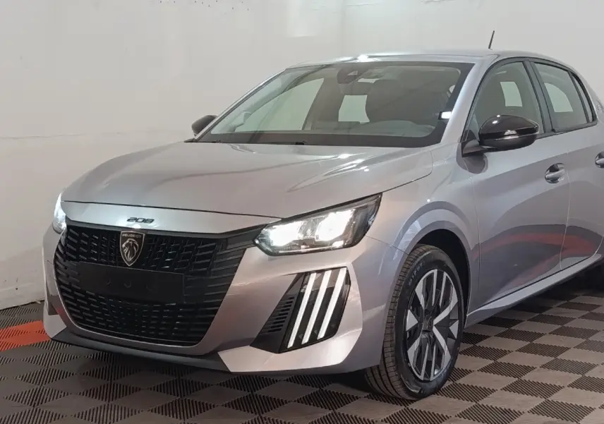 Peugeot 208 électrique gris clair vue 3/4 avant avec phares LED allumés et calandre noire distinctive.
