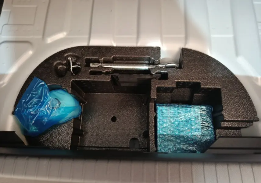 Rangement sous coffre de Peugeot 208 électrique 2024, compartiments en mousse noire avec outils et accessoires emballés.